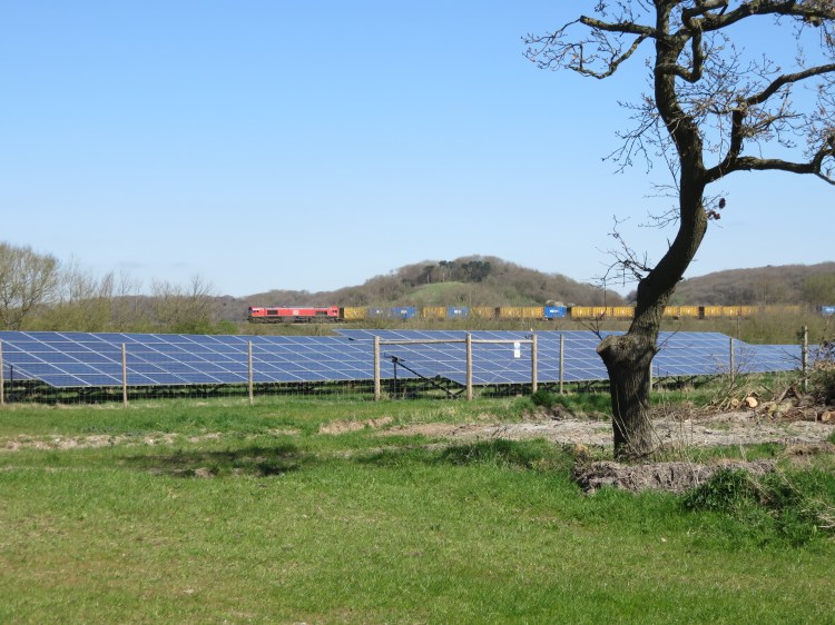 A freight train crosses the view northeast from the long field